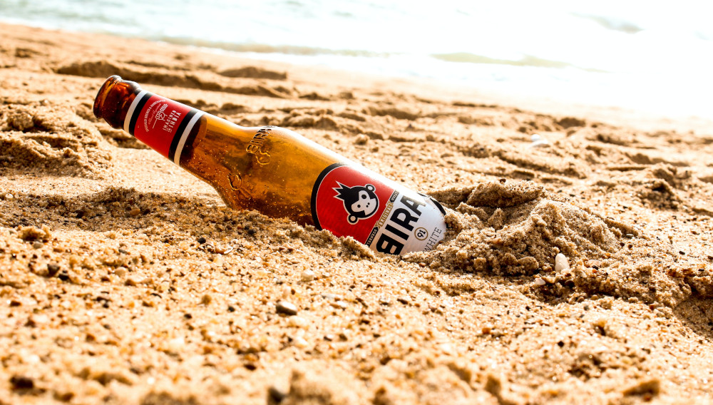 Bottle of Bira 91 lying in the sand (Photo: Jaydeep Kaila, Unsplash)