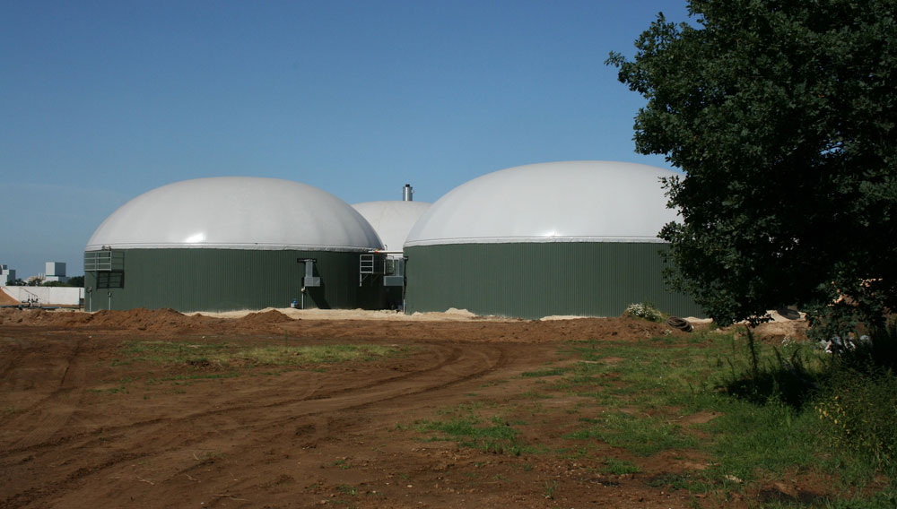 Blick auf eine Biogasanlage hinter unbewirtschaftetem Acker (Foto: Jan Nijman auf Pixabay)