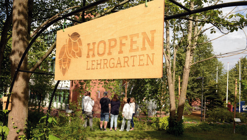 Holzschild mit der Aufschrift „Hopfengarten“ am Campus in Flensburg