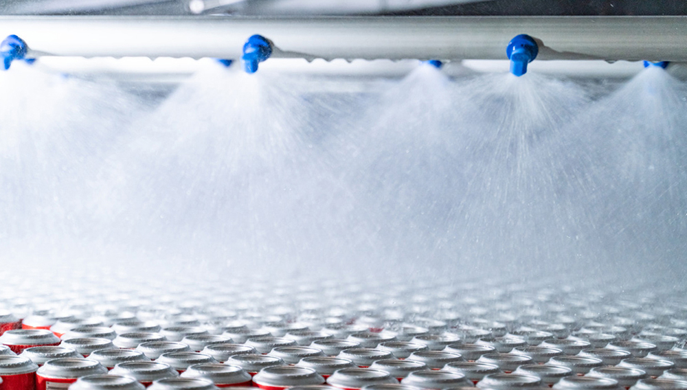 Auch die Wärmeenergie des Pasteurs lässt sich unter Umständen recyceln Getränkedosen werden im Tunnelpasteur mit Wasser zur Abkühlung beregnet
