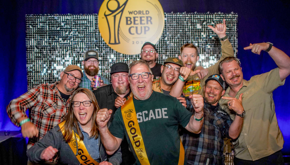 Ein Traum wird wahr: Gold beim World Beer Cup Zehn Personen jubeln in die Kamera. Sie stehen auf einer Bühne vor dem Logo des World Beer Cup 2025 (Foto: BA)