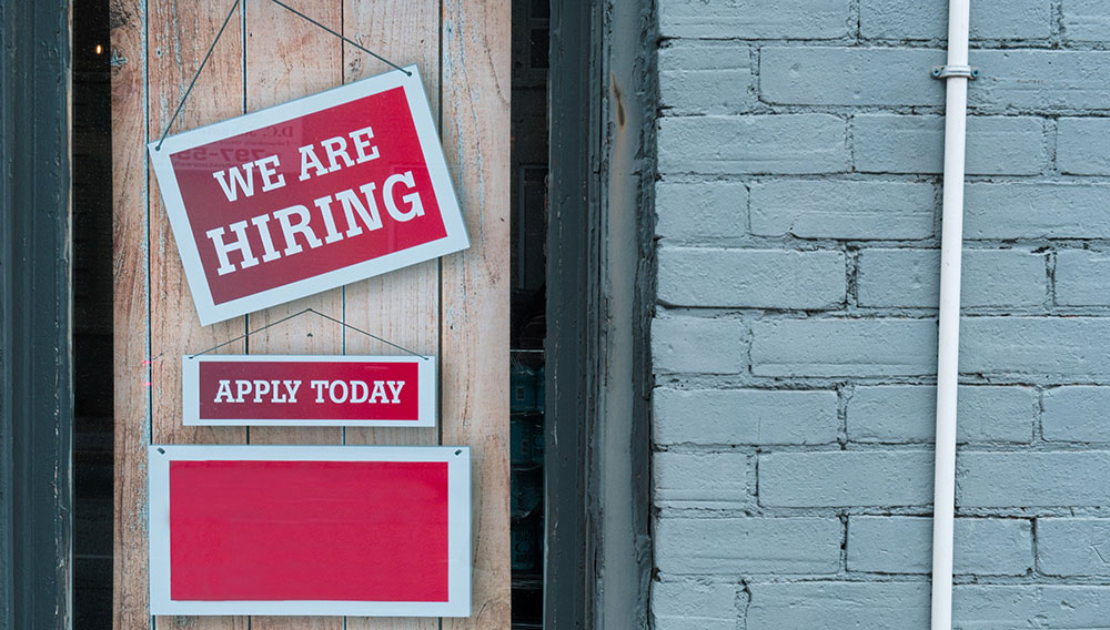 Grundsätzliche Frage: Wie stelle ich für mein Unternehmen die Attraktivität als Arbeitgeber in den Vordergrund? (Foto: Eric Prouzet auf Unsplash) Wand mit Fenster und Schild We are hiring (Foto: Eric Prouzet auf Unsplash)