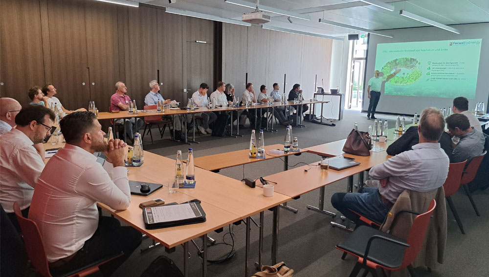 Technik und Know-how aus Dänemark für deutsche Firmen Blick in einen Konferenzraum, Menschen hören einer Person vor einem Bildschirm zu