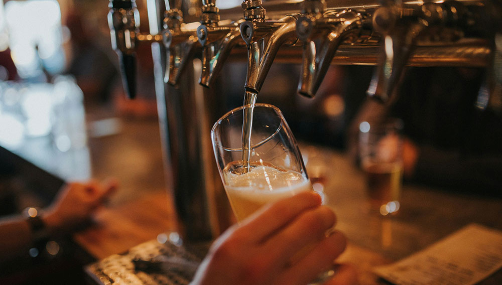 Person zapft Bier in ein Glas (Foto: Amie Johnson auf Unsplash)
