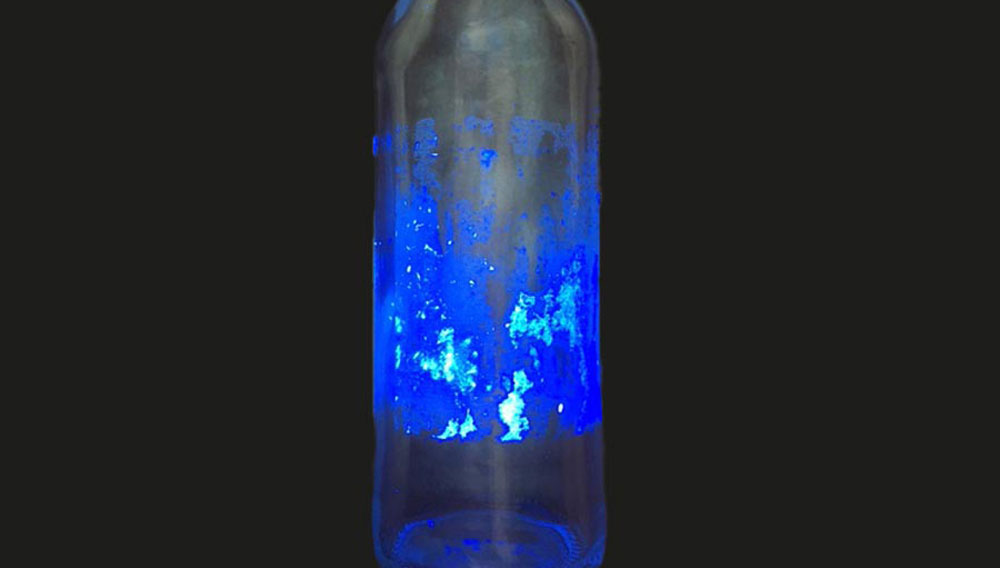Kleberückstände auf einer Flasche unter UV-Licht (Foto: miho)