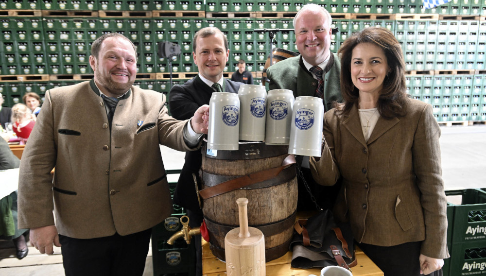 Vier Personen prosten mit Steinkrügen in die Kamera